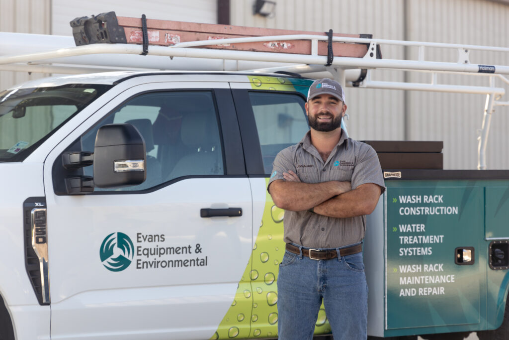 Evans Equipment Technician with Wash Bay Service Truck Evans Equipment & Environmental technician standing in front of service truck used for heavy equipment wash solutions, wash rack construction, and water treatment systems