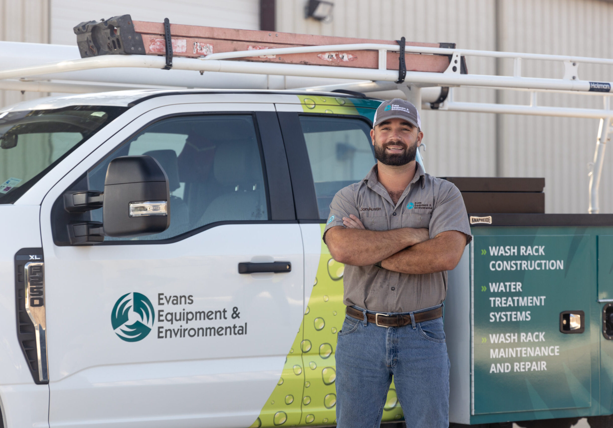 Evans Equipment Technician with Wash Bay Service Truck Evans Equipment & Environmental technician standing in front of service truck used for heavy equipment wash solutions, wash rack construction, and water treatment systems